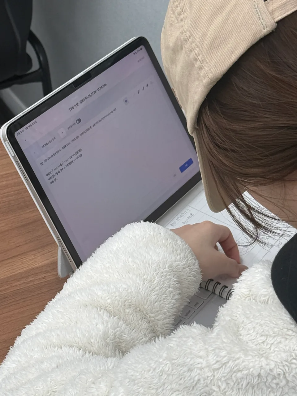 학생이 태블릿으로 오답 유형 문제를 확인하며 노트에 직접 풀이 과정을 쓰고 있는 모습